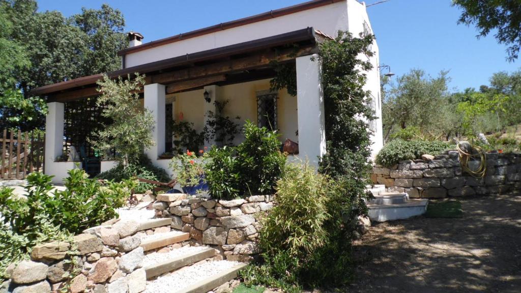 una pequeña casa con una pared de piedra delante de ella en Villa Ferulas, en Oliena