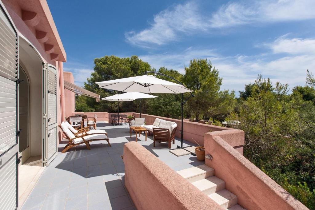 a patio with chairs and a table and an umbrella at Villa Merienne by BarbarHouse in Leuca