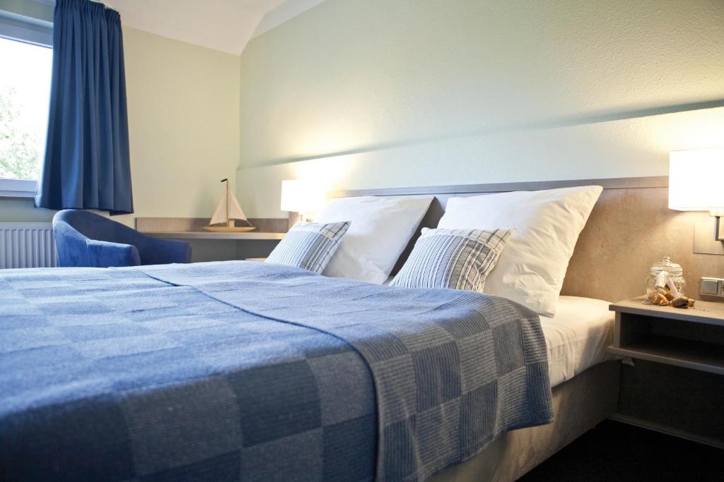 a bedroom with a blue and white bed and a window at Hotel Landhaus Leuchtfeuer Nordseeinsel Pellworm in Pellworm