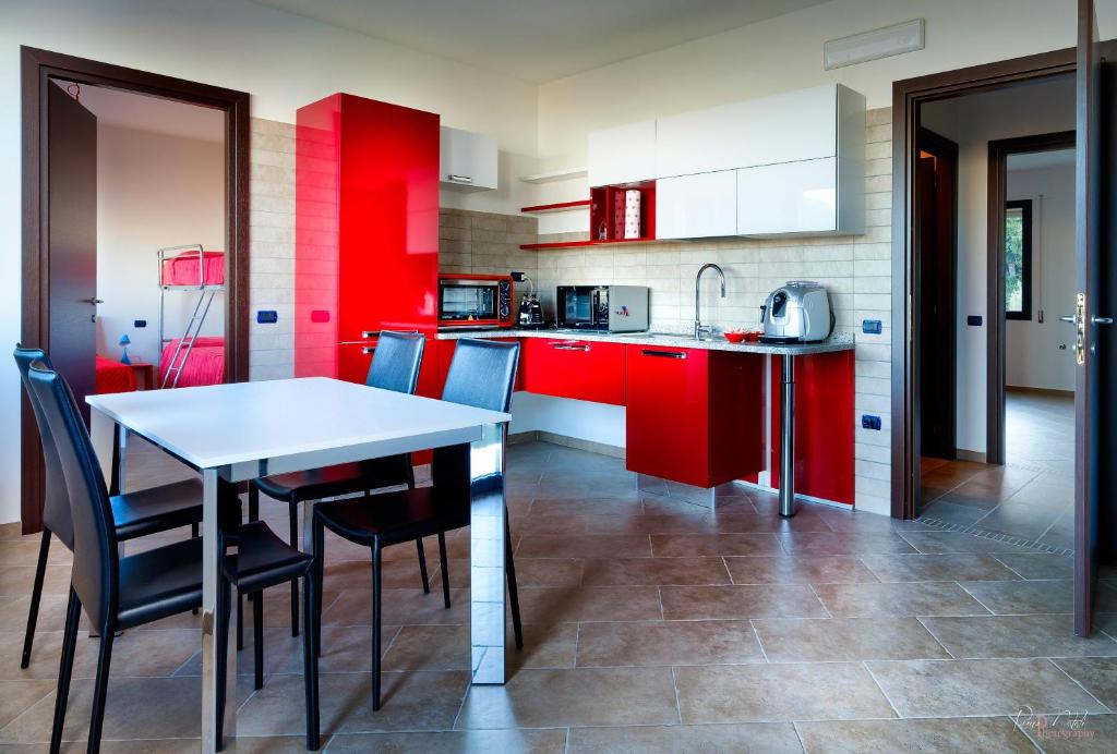 cocina con armarios rojos, mesa y sillas en Su AlevraXi, en Villagrande Strisaili