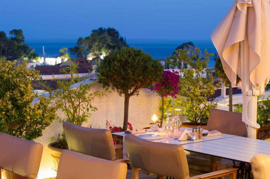 a table with chairs and an umbrella on a patio at Olympic Hotel in Parga