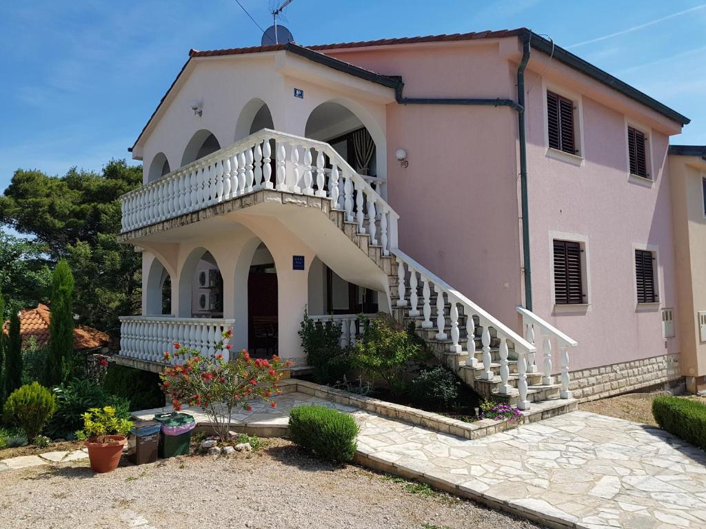 a large pink house with a staircase in front of it at Apartment Ruzmarin in Šilo