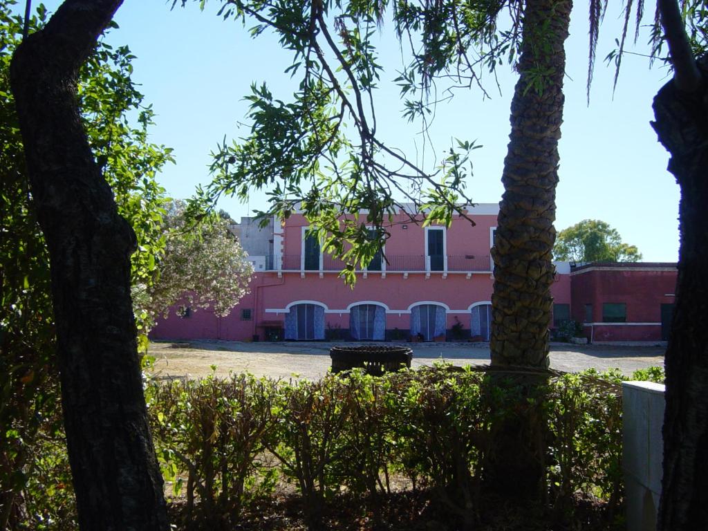a pink building in the middle of a park with trees at Tenuta Argiano in Mesagne