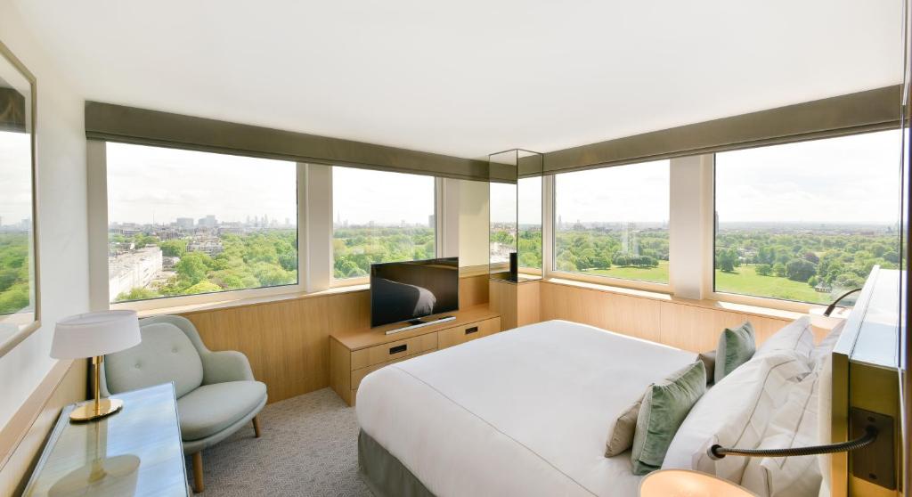 a bedroom with a bed and a tv and windows at Royal Lancaster London in London