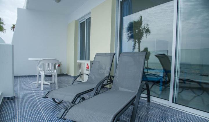 Paphinia SeaView Apartments في بافوس: غرفة بها كراسي وشرفة مطلة على المحيط
