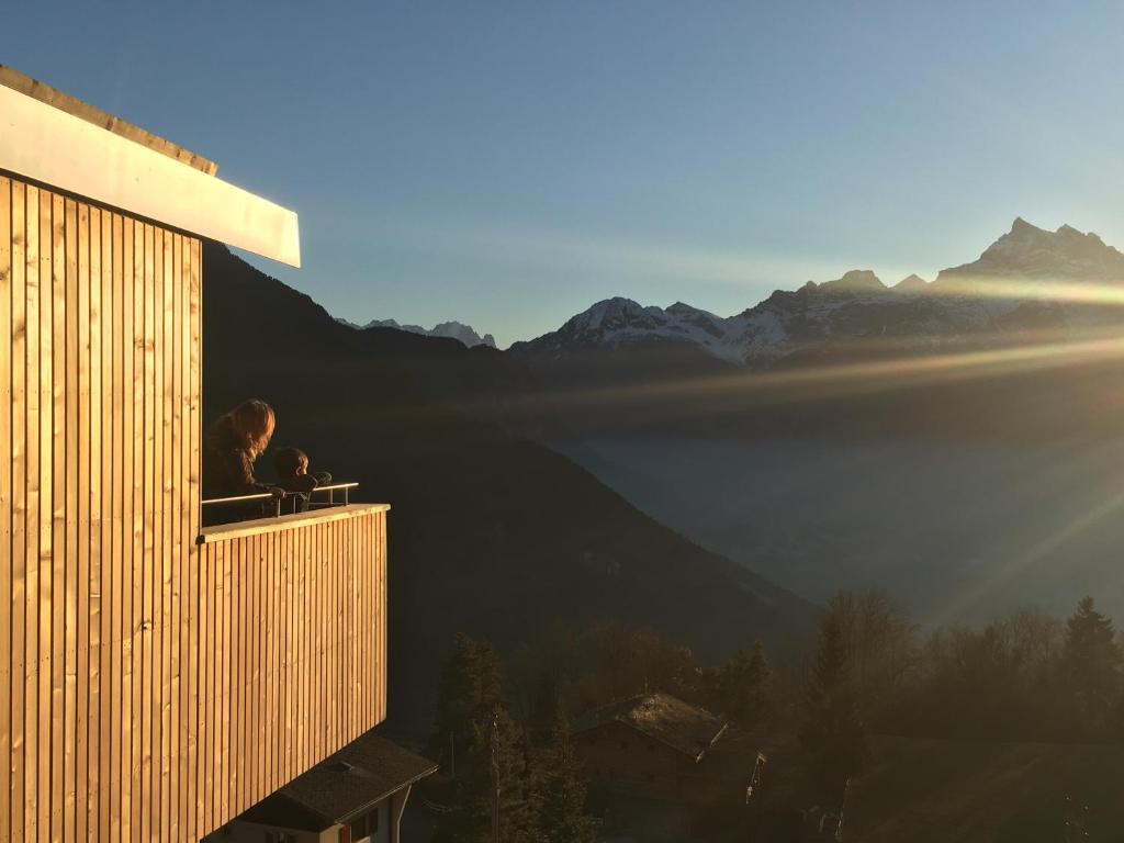 Dos personas sentadas en un balcón con vistas a las montañas en Chalet contemporain, en Gryon