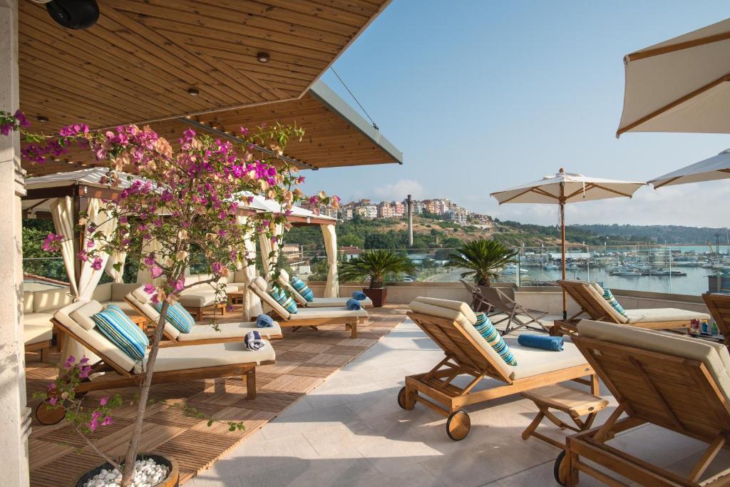 a patio area with chairs, tables and umbrellas at Blu Bay Hotel Sozopol in Sozopol