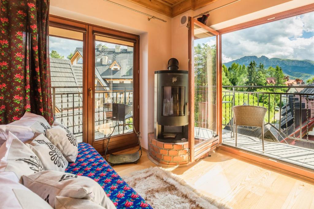 a living room with a fireplace and a large window at Apartamenty Smrekowa Tatry Zakopane in Zakopane