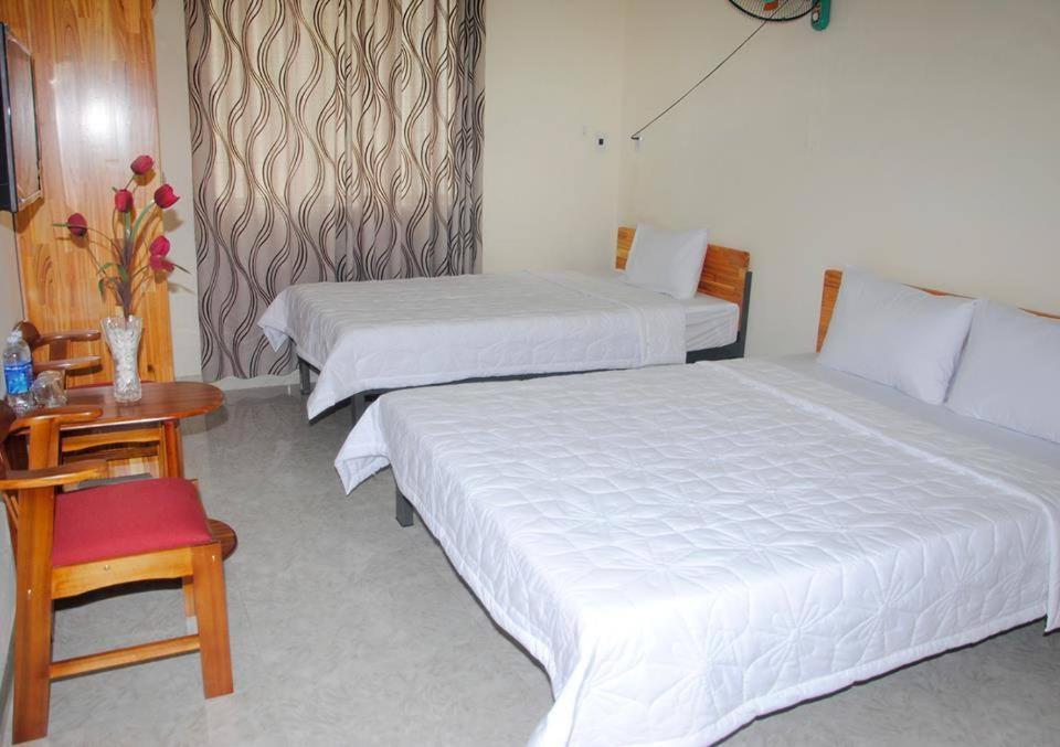 duas camas num quarto de hotel com uma mesa e cadeiras em Hostel 15A em Da Nang