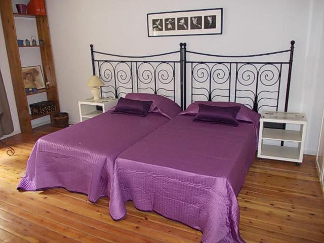 Cama grande de color púrpura con sábanas y almohadas de color púrpura en La Posada de San Marcial, en Tudela