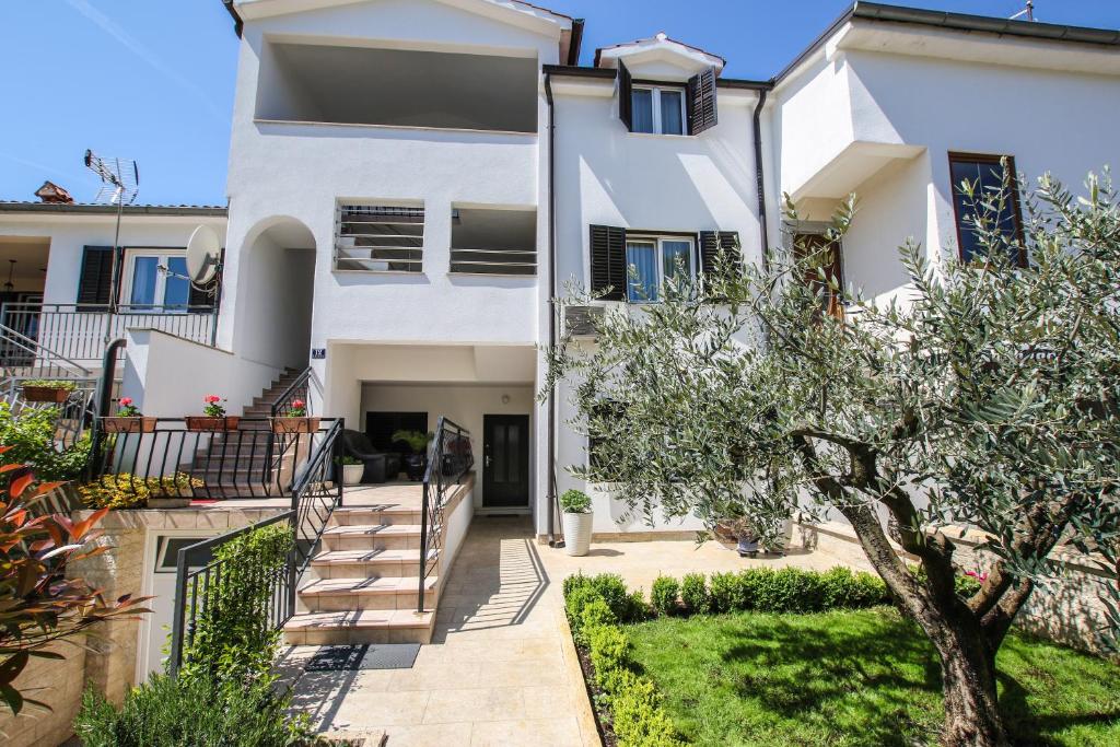 a white house with a staircase and a tree at Apartman Mila in Poreč
