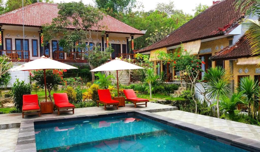 a resort with a swimming pool and chairs and umbrellas at Kusuma Abiakta Sea Side Lembongan in Nusa Lembongan