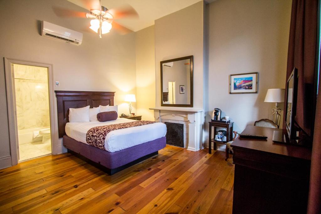 a bedroom with a bed and a fireplace and a mirror at Inn on St. Ann, a French Quarter Guest Houses Property in New Orleans