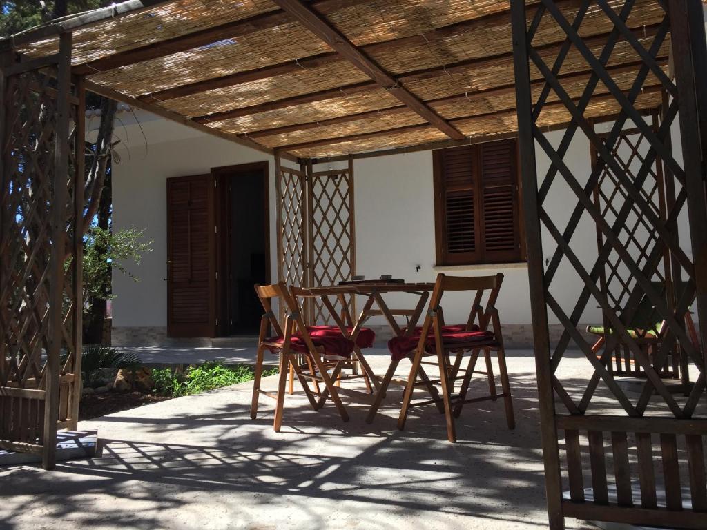 a patio with a table and chairs under a wooden pergola at Casa Scalia in Custonaci