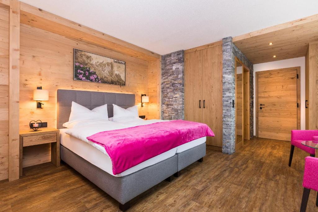 a bedroom with a large bed with a pink blanket at Hotel Augarten in Neustift im Stubaital