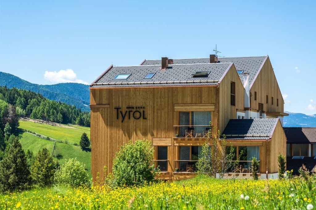 une maison en bois avec des panneaux solaires dans un champ dans l'établissement Hotel Tyrol, à Funes