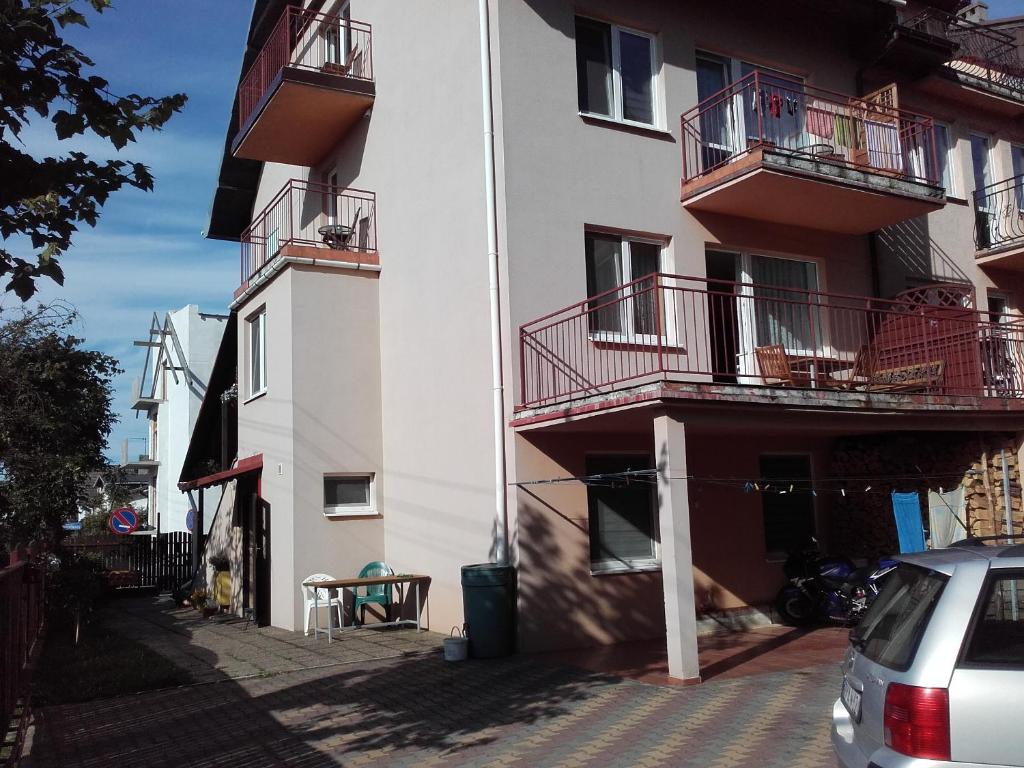 un edificio con balcones y un coche estacionado al lado en Pokoje u Bogusi en Międzyzdroje