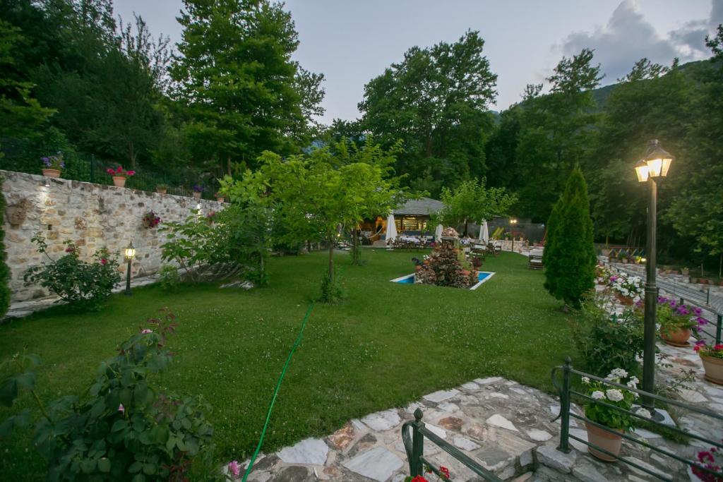 a yard with a stone wall and a garden with flowers at Neromylos in Nikísiani