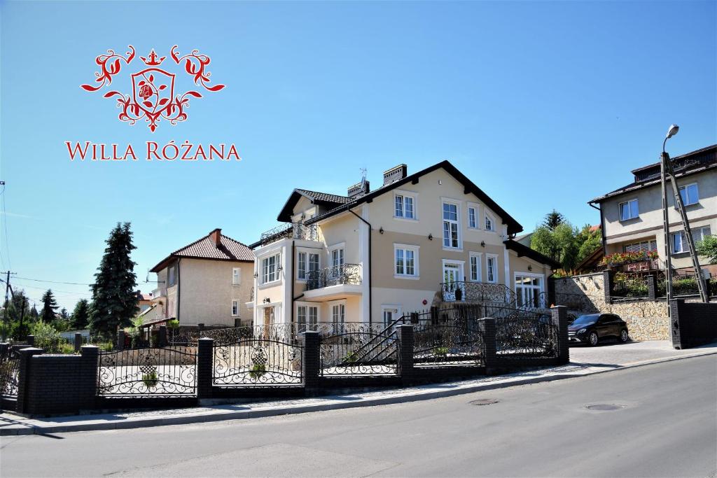 a white house on the side of a street at Willa Różana - Apartamenty i Pokoje Gościnne in Sandomierz