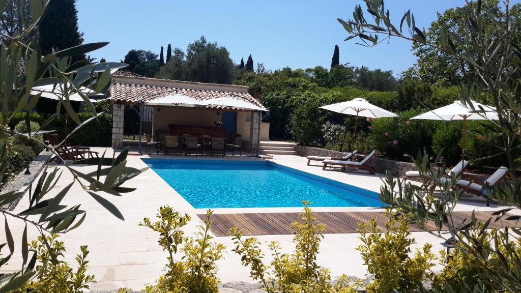 a swimming pool in a backyard with umbrellas at Aux charmes de grasse in Grasse