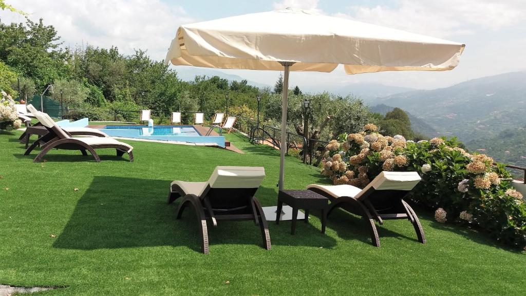 een groep stoelen en een parasol naast een zwembad bij Casa Nova Agroturismo in Resende