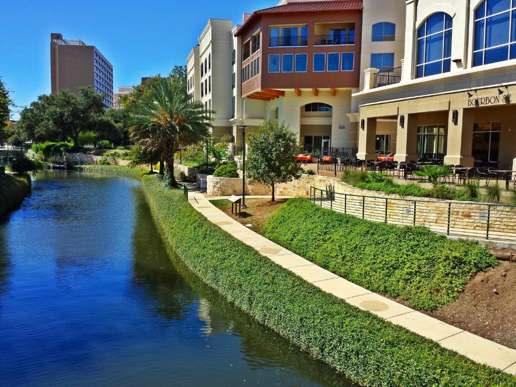 a river in front of a building next to a building at Wyndham Garden River Walk Museum Reach in San Antonio