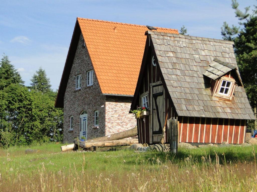 une maison ancienne avec un toit orange dans un champ dans l'établissement Bispinger-Heidezauber, à Bispingen