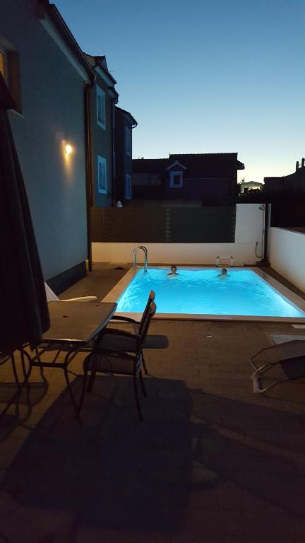 a swimming pool with two chairs next to a building at Ljiljana in Srima