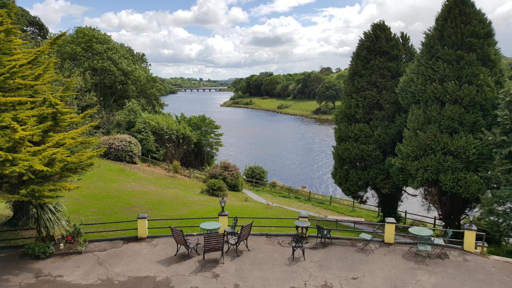 a view of a river from a park with tables and chairs at Coolcower House in Macroom