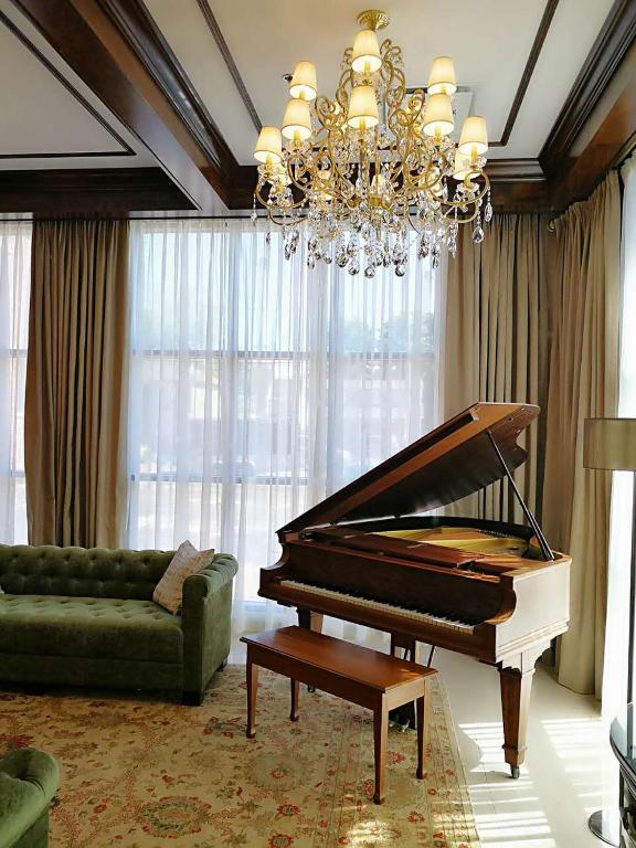 a living room with a piano and a chandelier at Sydney Boutique Inn & Suites in Charlottetown