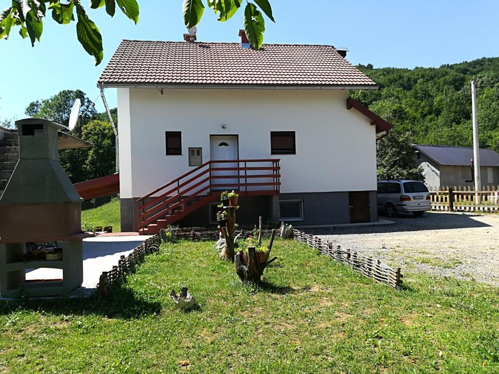 un petit bâtiment blanc avec une clôture devant lui dans l'établissement Guesthouse Bubalo, à Drežnik Grad