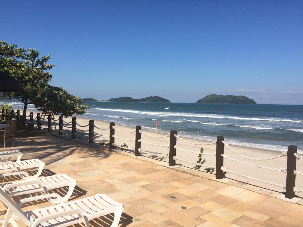 Juquehy - Condomínio de Frente para o Mar في جوكاي: صف من الكراسي البيضاء على الشاطئ