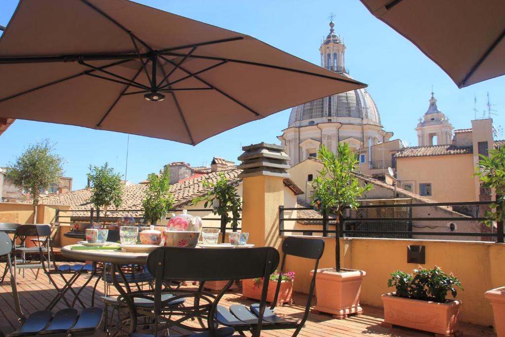 eine Terrasse mit einem Tisch, Stühlen und einem Sonnenschirm in der Unterkunft Navona Residenza de Charme in Rom
