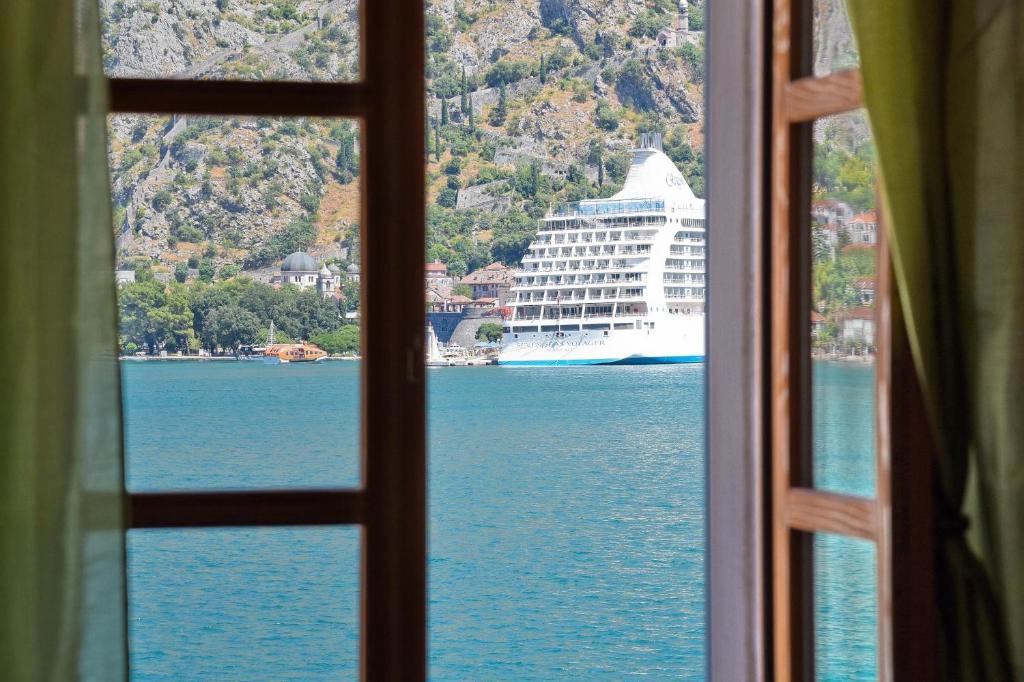 um navio de cruzeiro na água visto de uma janela em Ribica Apartments em Kotor