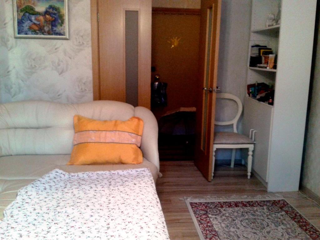 a living room with a white couch with an orange pillow at Rooms in Apartment on Tbilisskiy bulvar 11 in Yekaterinburg