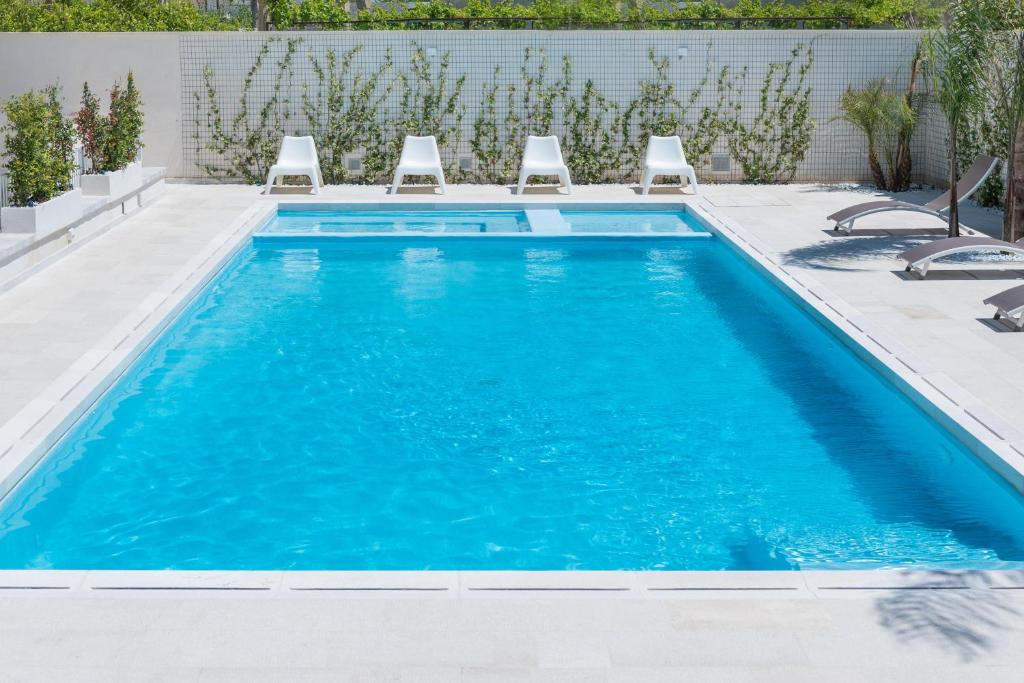 una piscina con sillas y agua azul en Calura Residence, en Carpignano Salentino