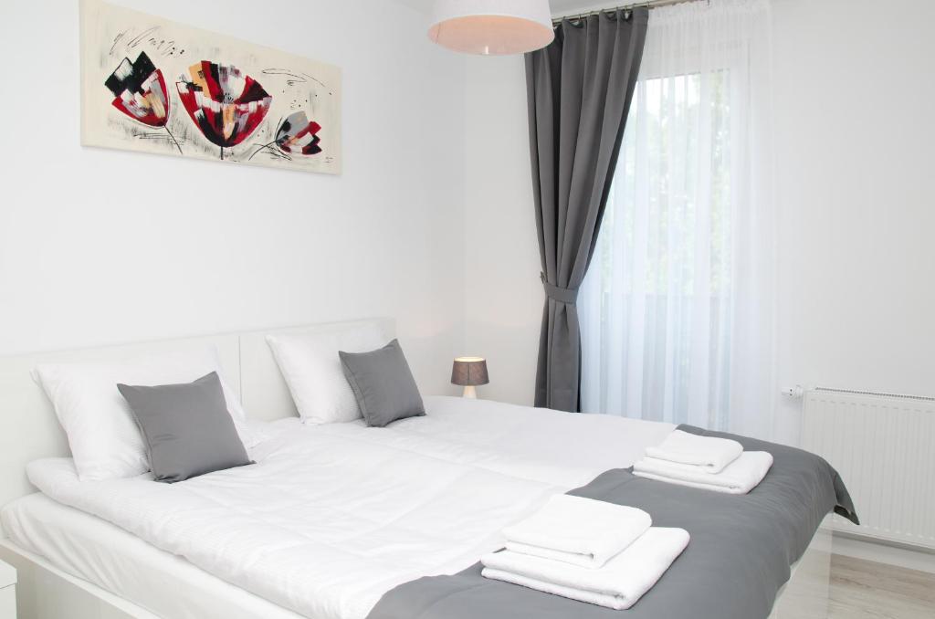 a white bed with two towels on top of it at Apartamenty Mariela-Kołobrzeg z garażem in Kołobrzeg