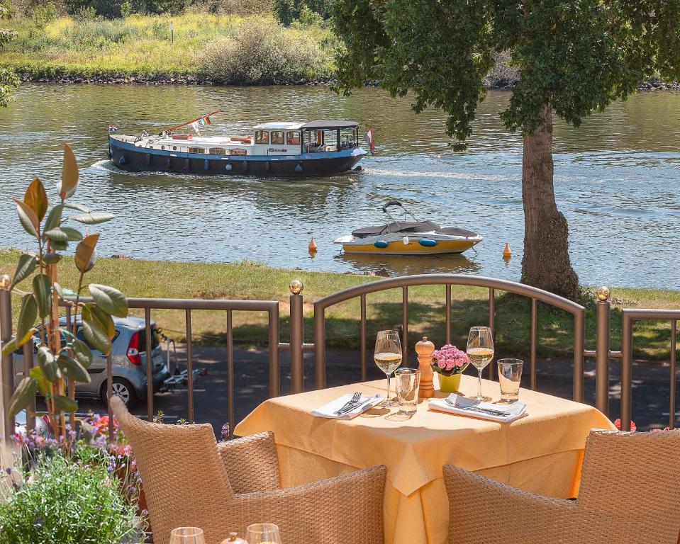a table with wine glasses and a boat in the water at Hotel Zur Traube in Ürzig