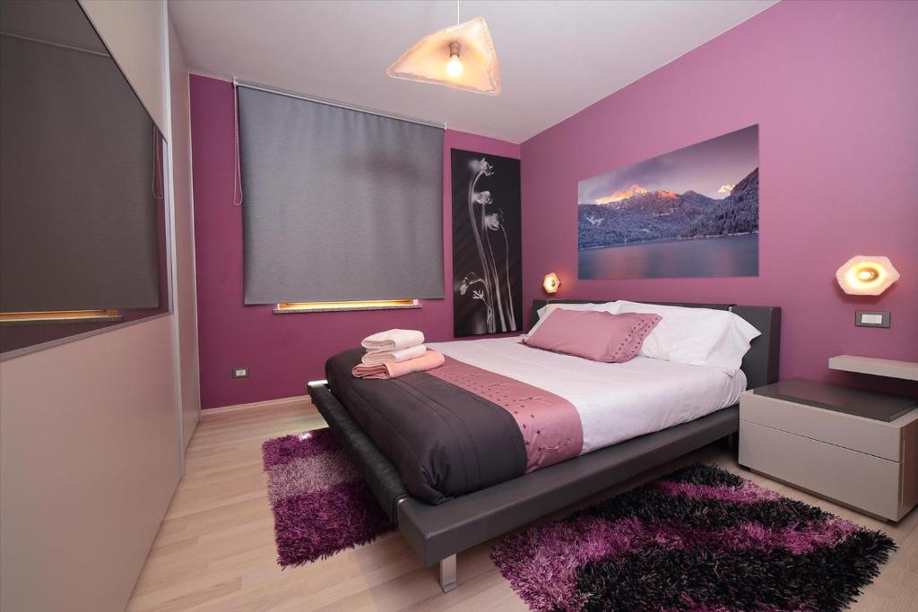 a purple bedroom with a bed and a large window at Affittacamere da Jasmina Venzone in Venzone