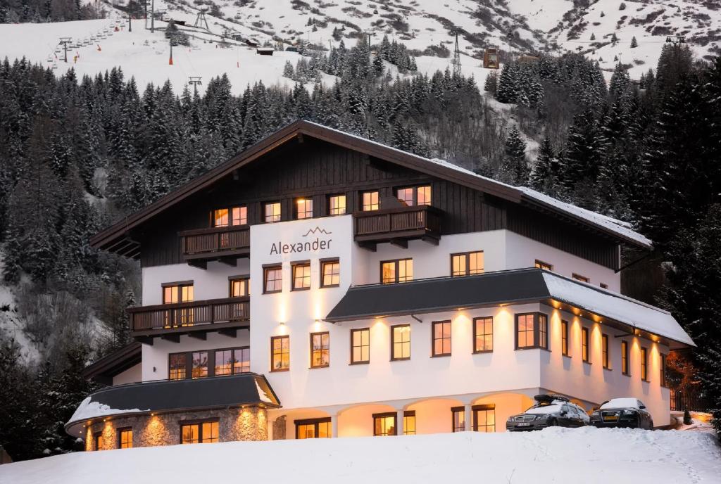 Un grand bâtiment avec des lumières allumées dans la neige dans l'établissement Appartements Alexander, à Fiss