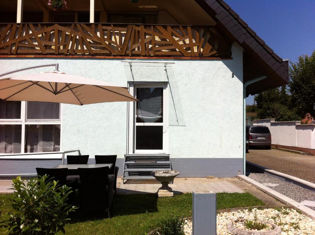 a white house with a table and an umbrella at A & J Ferienwohnung Hirsch in Rust