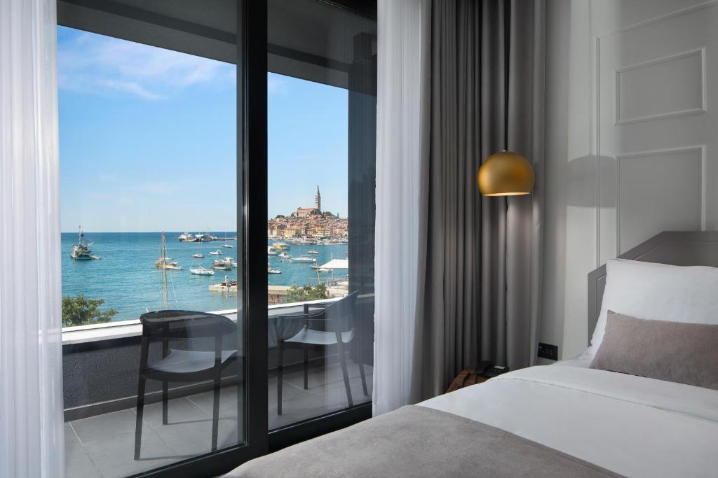 a bedroom with a bed and a view of the ocean at Hotel Delfin in Rovinj