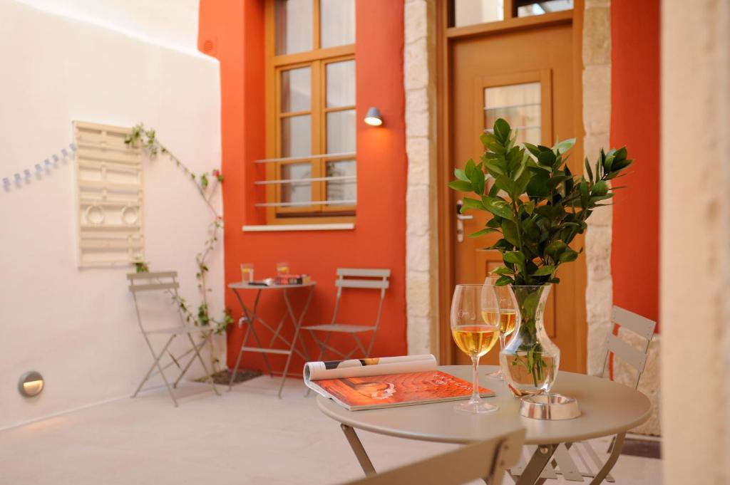 een tafel met twee glazen wijn en een vaas met bloemen bij Veranda Rossa Suites in Rethimnon