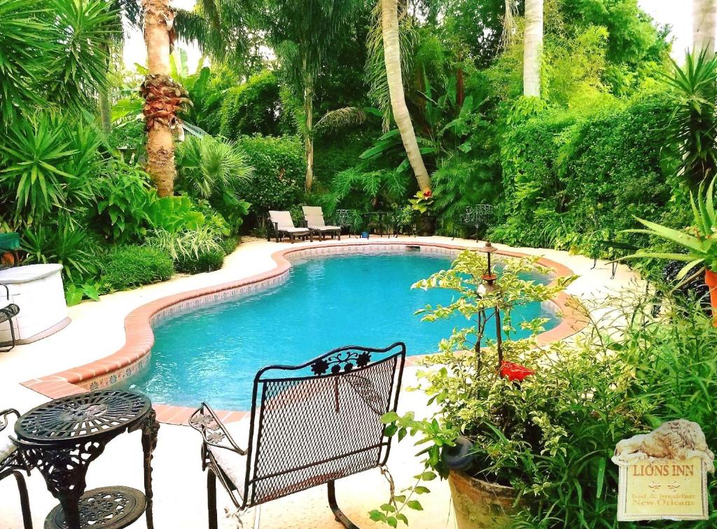 a swimming pool in a garden with a table and chairs at Lions Inn Bed & Breakfast in New Orleans