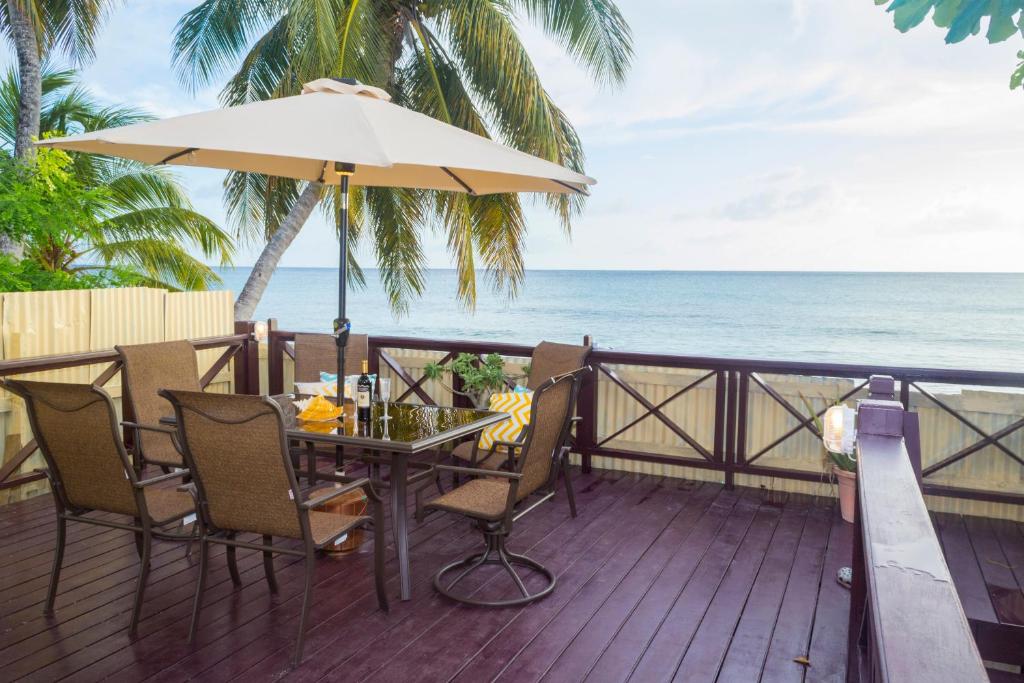 a table and chairs on a deck with the ocean at Darrel Cot Beachfront Cottage in Saint Peter