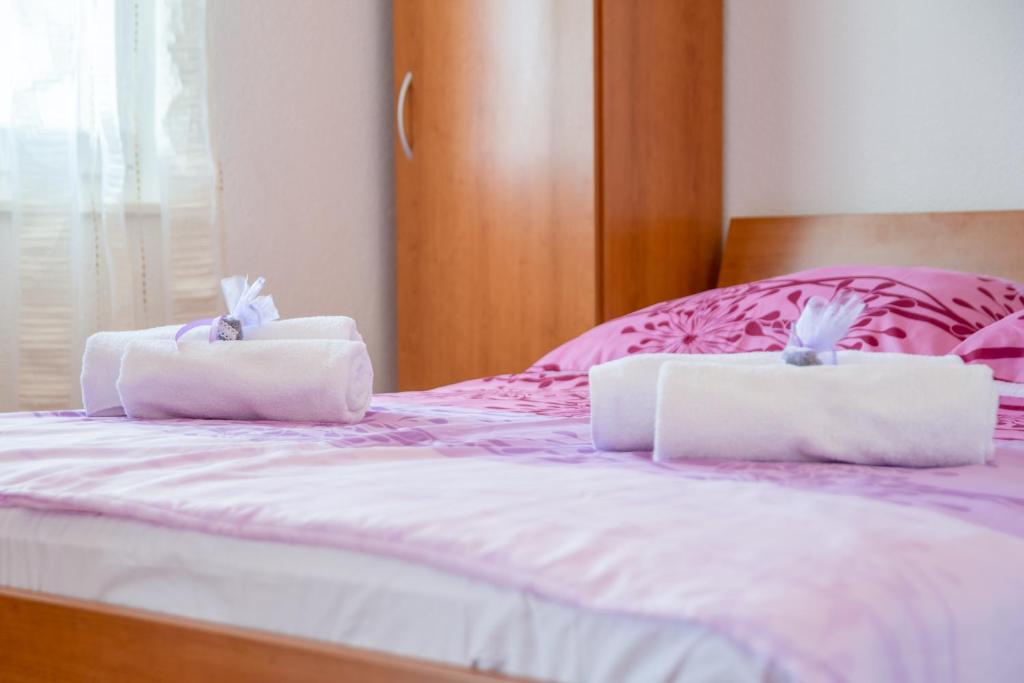 dos toallas blancas sentadas encima de una cama en Apartments Šimić, en Milna