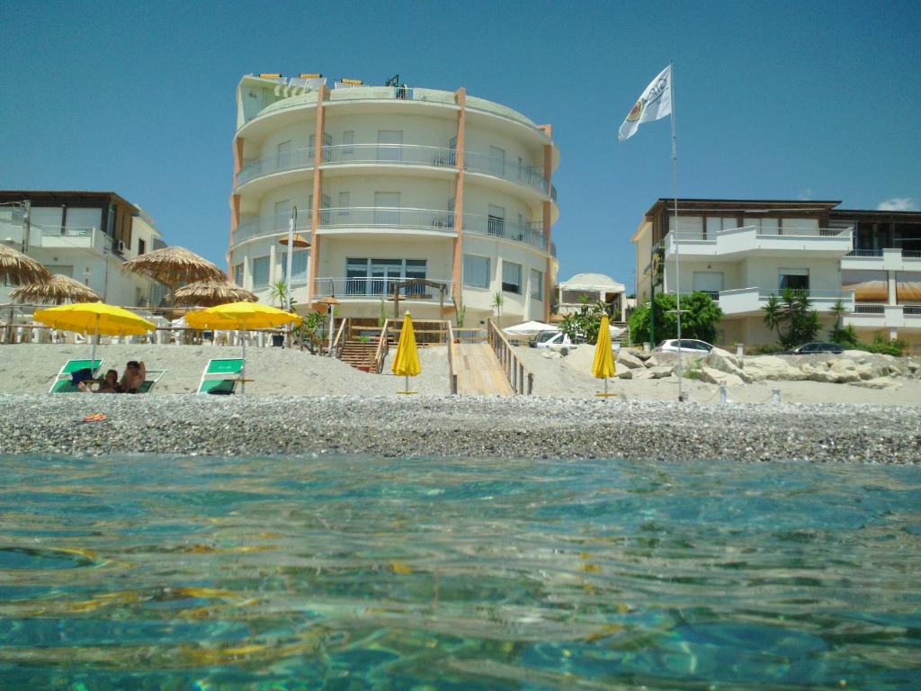 a building on the beach with chairs and umbrellas at Hotel Il Girasole in Bova Marina