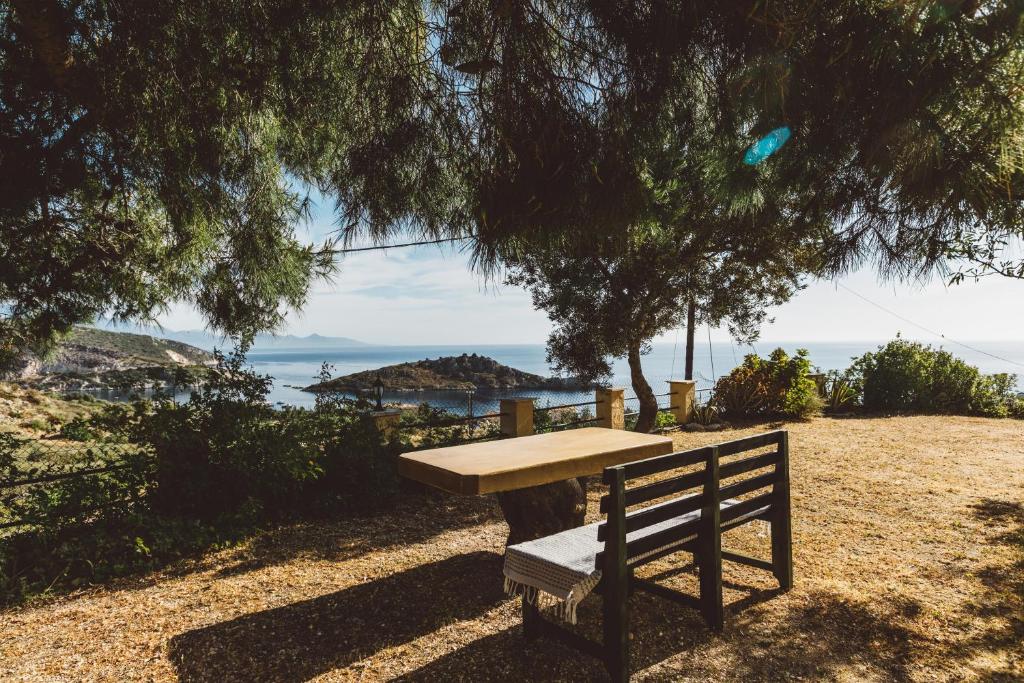 a wooden bench sitting under a tree near the ocean at Panorama Apartments updated with infinity pool in Agios Nikolaos