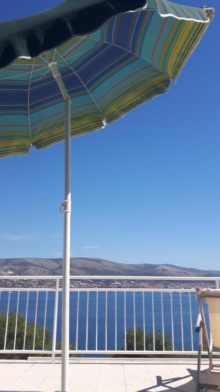 a umbrella on a balcony with a view of the water at Apartmani Gale in Okrug Donji