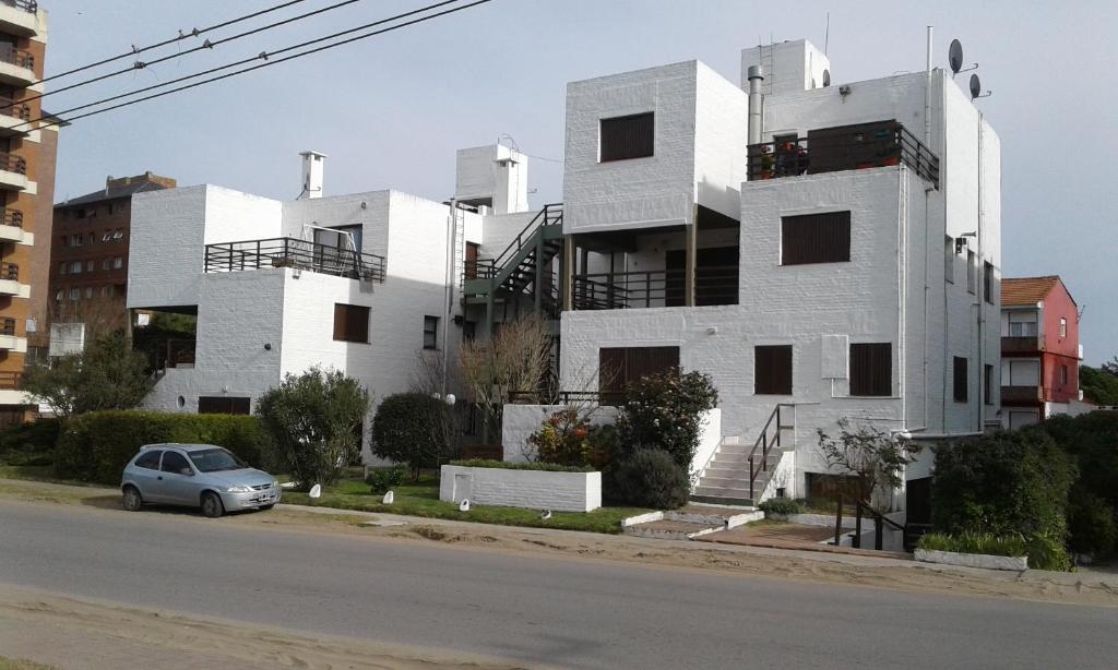 um edifício branco com um carro estacionado em frente em a 100mts de la PLAYA "Mar y Vida" em Pinamar